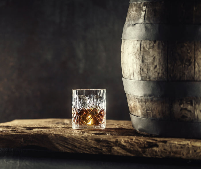 Whisky in a glass next to a whisky barrel. Aged whisky in a whisky glass. Spirits of France
